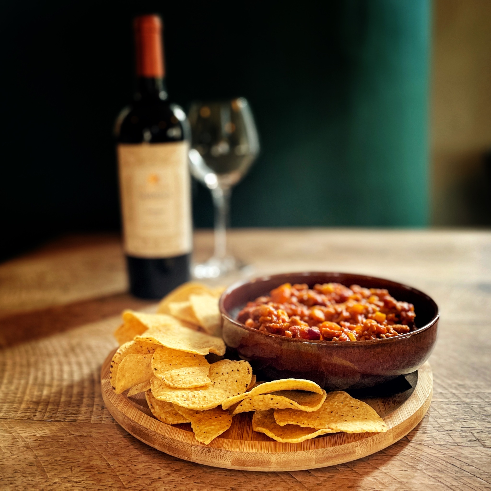 Nacho's met dip en rode wijn op tafel in De Proeverij